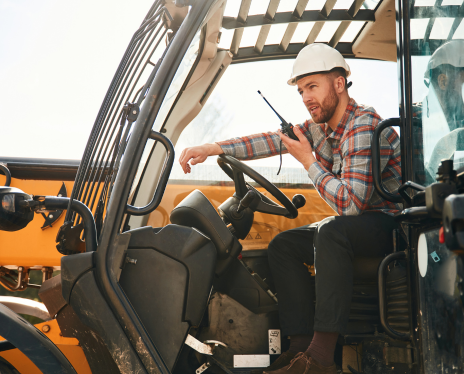 Male agricultural worker sitting in tractor talking on radio